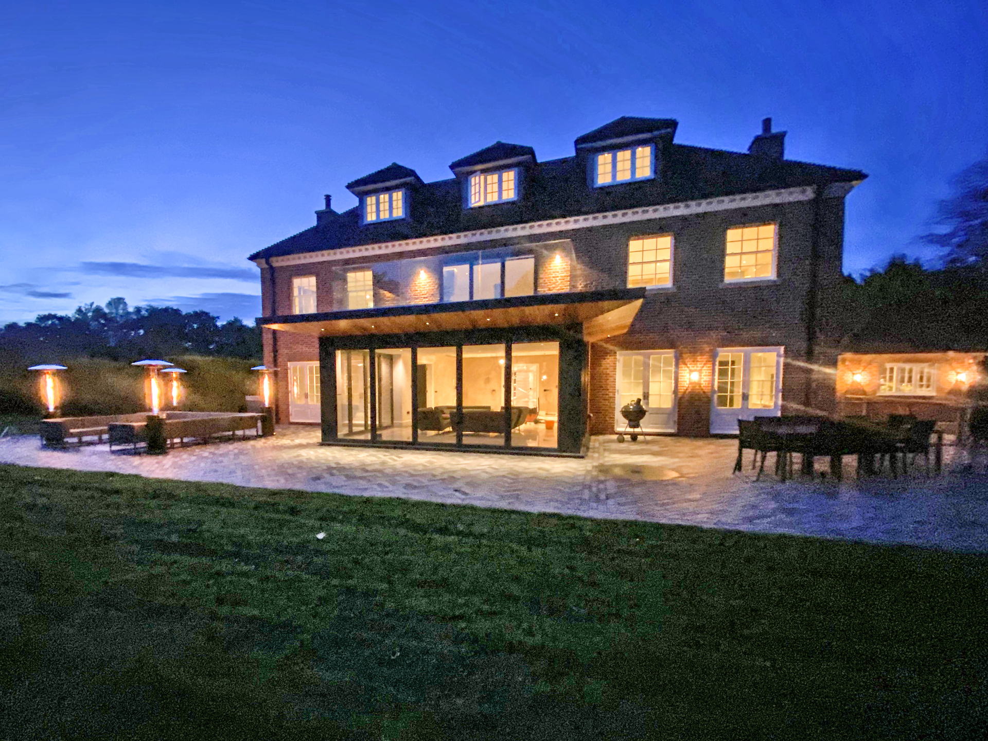 Rear view of luxury property at dusk with lights on