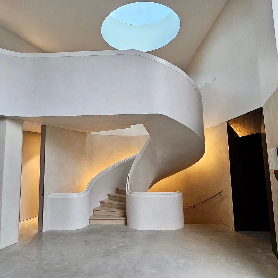 Ultra-modern curved staircase with attached handrails and timber treads